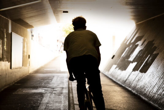 Urban bike rider from behind in tunnel.