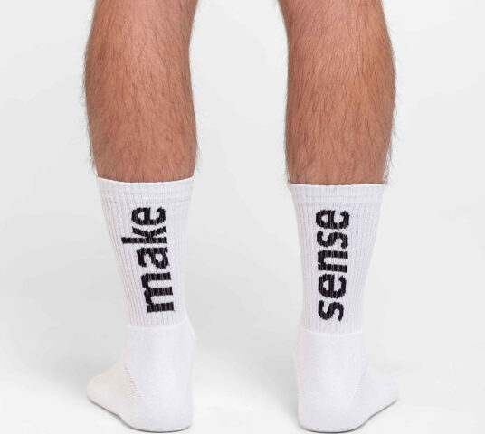 Man wearing white socks close up two feet from behind.